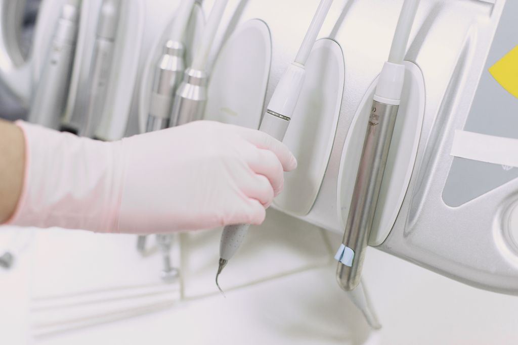 Close-up of a gloved hand operating dental tools in a sterile clinic environment.